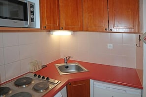 A compact kitchen with a microwave, stove, sink, and wooden cabinets. - Ski-in/ski-out & foot of the slopes, 2nd floor, view ski slopes, swimming pool, sauna, balcony, tv (Les Orres)
