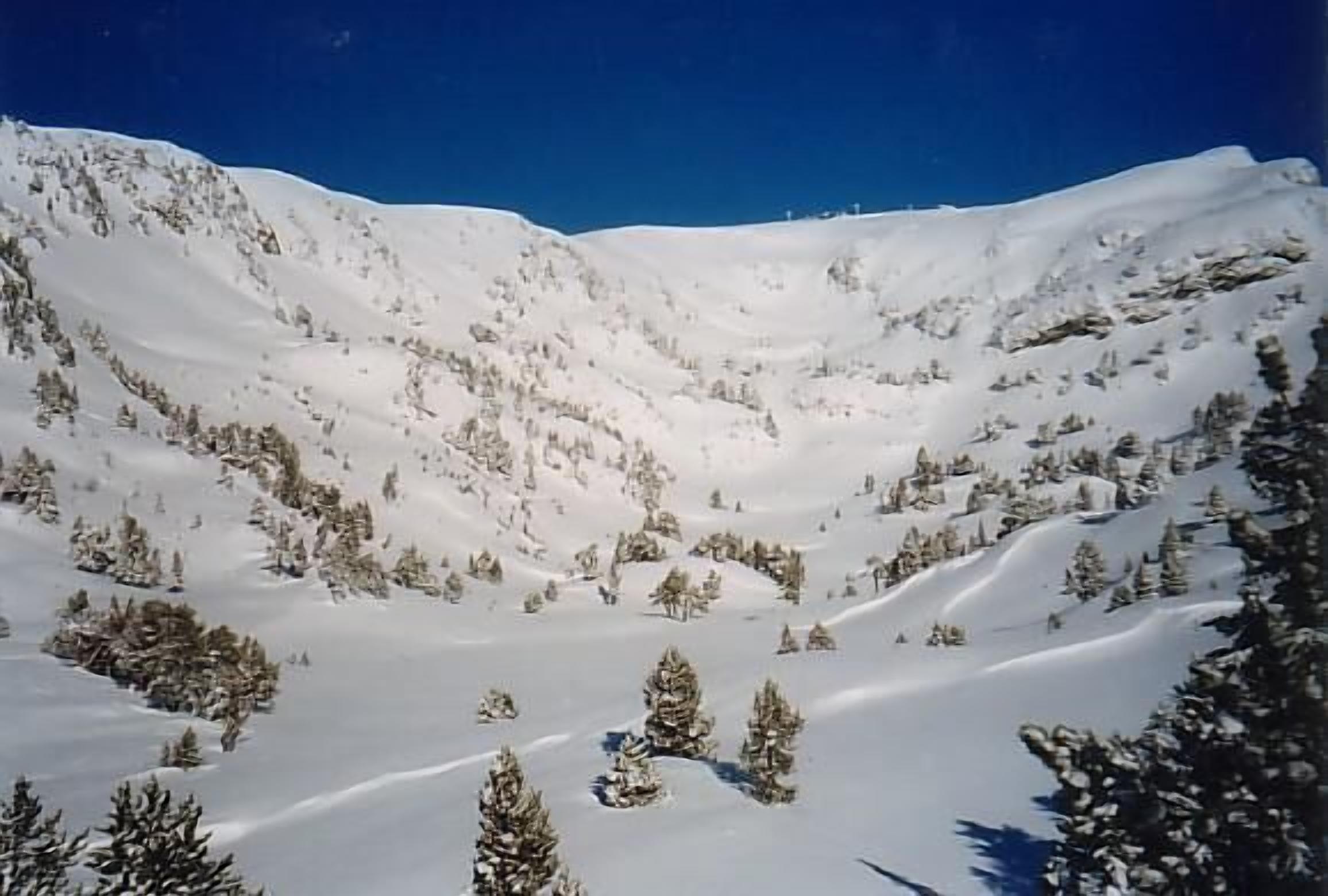 A snow-covered mountain landscape with clear skies.