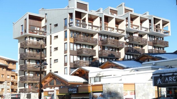 Un hôtel à plusieurs étages doté de balcons, un magasin Sherpa et un magasin ARC.