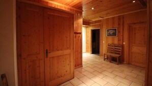 Un intérieur en bois avec un sol carrelé, un banc et une porte.