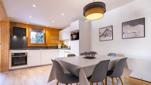 Una cocina moderna con detalles de madera, un comedor con mesa y sillas, y un ventanal grande.
