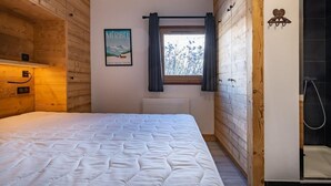 Un dormitorio con cama, ventana con cortinas, un cartel en la pared y un armario de madera.