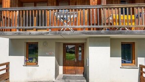 Een houten gebouw met een balkon, een deur en kleine ramen.