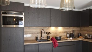 Eine moderne Küche mit dunklen Holzschränken, einer Edelstahl-Mikrowelle, einem Spülbecken mit Armatur und verschiedenen Küchengeräten.