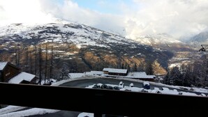 Paesaggio montano con pendii innevati e una seggiovia nella valle.