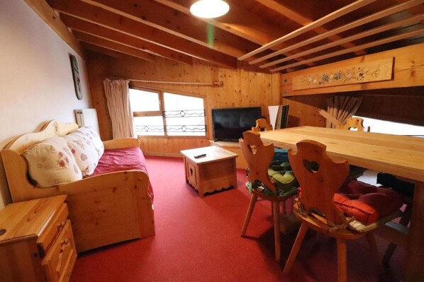 Relax in a serene space with a plush bed, wooden furniture, and a beautiful painting.