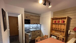 Eine kompakte Küche mit Holzausbau, einer eingebauten Mikrowelle und einer kleinen Essecke mit kariertem Tisch.