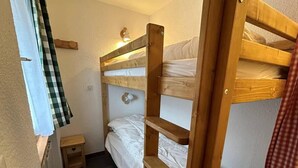 Ein Schlafraum mit Etagenbetten, einem kleinen Nachttisch und einer Wandleuchte.