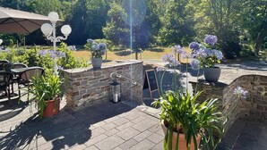 An outdoor patio area with stone walls, potted plants, and outdoor seating. - Hotel Alte Mühle (Bad Bertrich)
