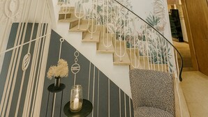 A staircase with a floral mural, a hanging light fixture, and a patterned wall. - Hotel Alte Mühle (Bad Bertrich)