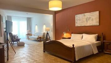 Ein Hotelzimmer mit einem hölzernen Bett, einem großen Gemälde an der Wand und Blick auf das angrenzende Zimmer.