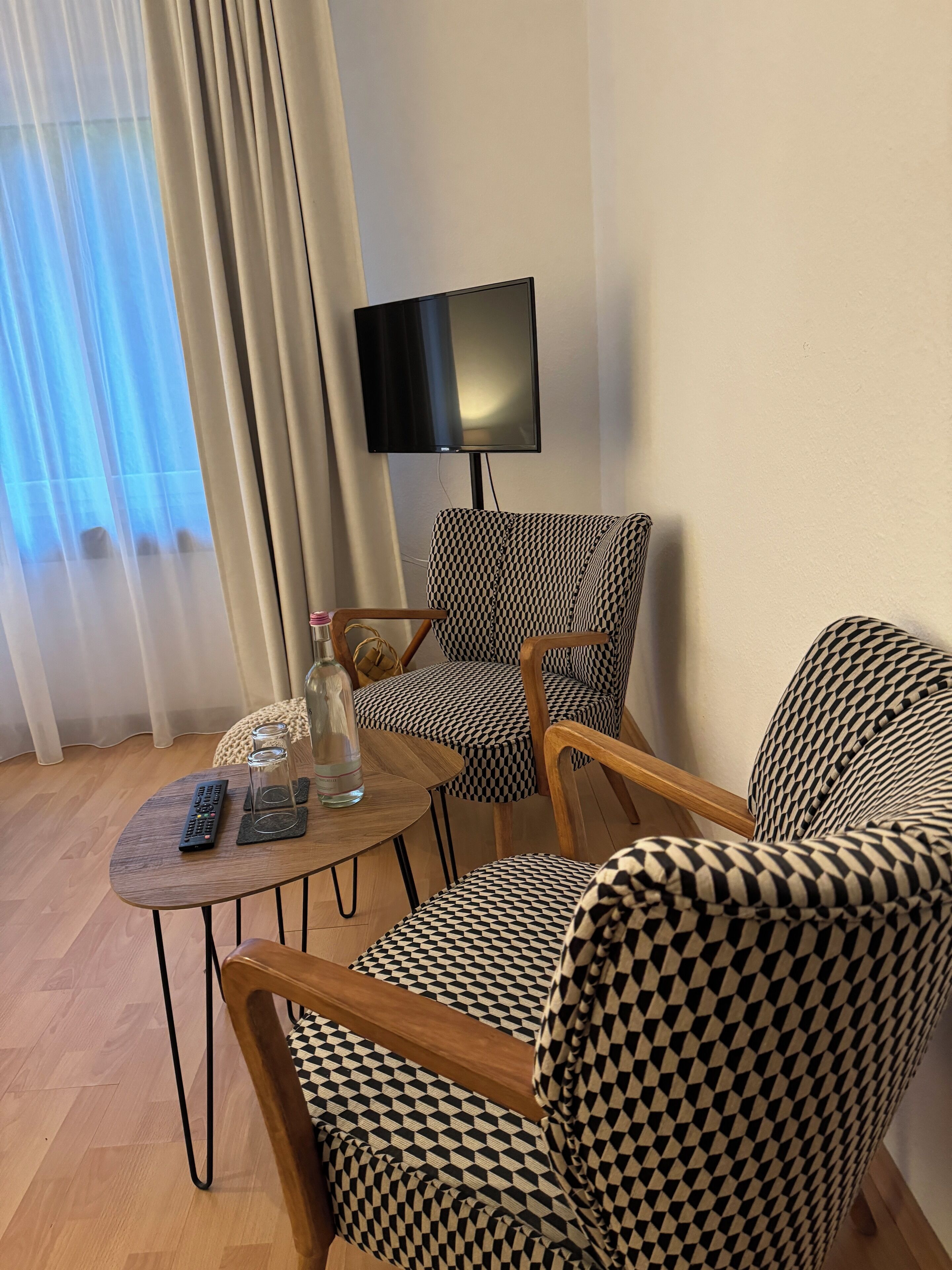 Een moderne woonkamer met een geruit bankstel, een houten salontafel en een aan de muur bevestigde televisie.
