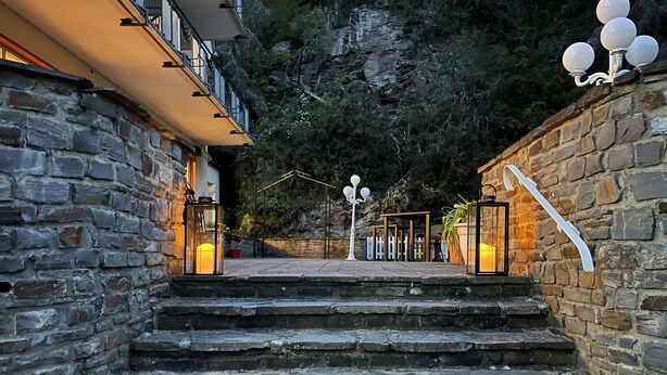 A stone staircase leading to a building with a balcony, surrounded by a stone wall and a view of a rocky hillside. - Hotel Alte Mühle (Bad Bertrich)