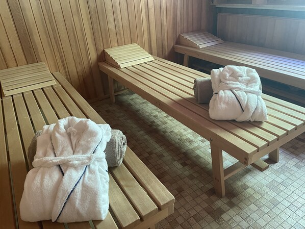 Un cuarto de sauna con bancos de madera, toallas y un banco con una toalla.