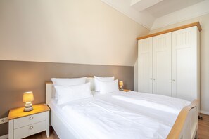 Ein Schlafzimmer mit Bett, Nachttisch, Lampe und Kleiderschrank.