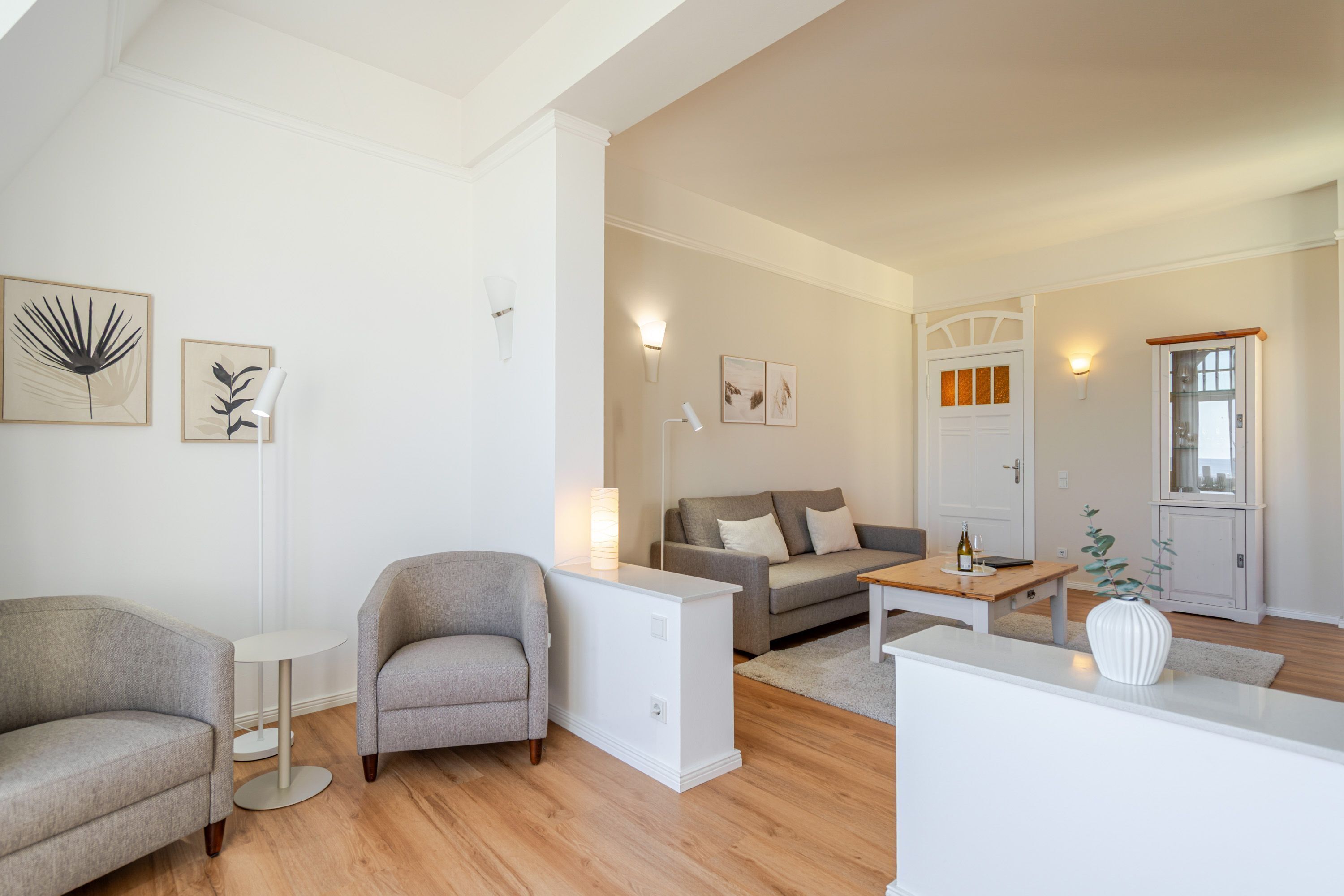 En moderne stue med sofa, lænestol, sofabord og et lille hvidt bord.