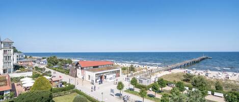 Un hôtel situé sur la côte, avec vue sur la plage, une jetée et un parking.