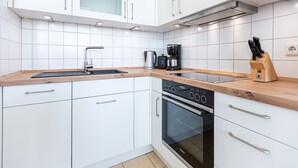 Una cucina moderna con mobili bianchi, un lavello in acciaio inossidabile, una macchina da caffè e un forno.