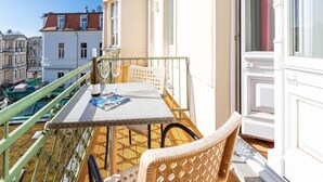 Un balcone con tavolo, sedie e una bottiglia di vino.