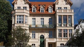 Un edificio storico con facciata simmetrica, ampie finestre e un ingresso centrale con una porta verde.