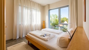 A bedroom with a large bed, a window with a view of greenery, and a small balcony. - Quartier II, App. 2.2 (Heringsdorf)