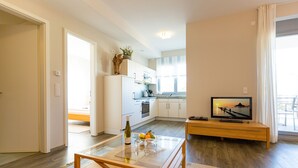 A modern living room with a glass coffee table, a sofa, and a television. - Quartier II, App. 2.2 (Heringsdorf)
