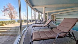 Zona junto a la piscina con tumbonas, vista al mar y un paseo cubierto.