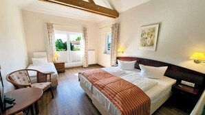 Una habitación de hotel con dos camas, un escritorio, una silla y una ventana con cortinas.