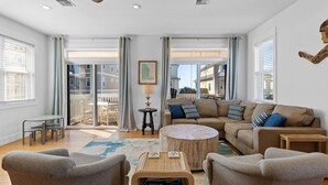 A spacious living room with a large sofa, two armchairs, a coffee table, and a dining area with a table and chairs. - Merry Mermaid - Gulf view, Easy beach access, Family and pet friendly (Cape San Blas)
