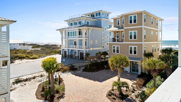 A multi-story beachfront property with a paved driveway, palm trees, and a view of the ocean. - Merry Mermaid - Gulf view, Easy beach access, Family and pet friendly (Cape San Blas)