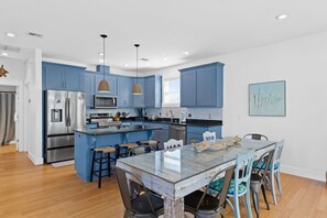 Une cuisine moderne avec des meubles bleus, des appareils en acier inoxydable et un îlot central doté de tabourets de bar.