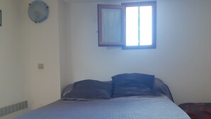 Ein Schlafzimmer mit Bett, Fenster und Wandventilator.