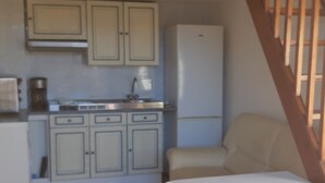 Eine Küche mit Schränken, einem Kühlschrank, einer Spüle und einer Holztreppe.