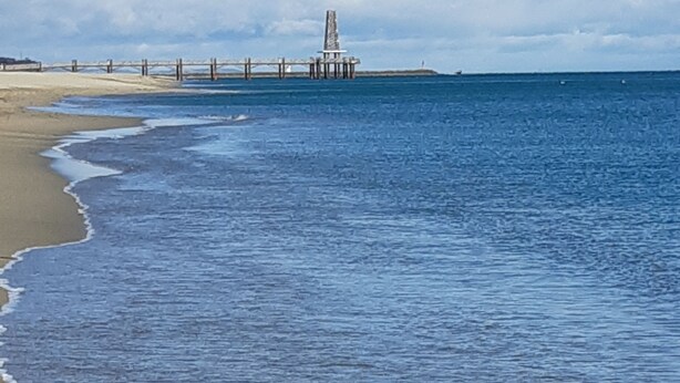 Ein Strand mit einem Steg, der ins Wasser führt.