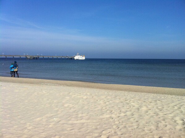 A sandy beach with a pier extending into the water.
