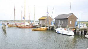 A harbor with several boats docked, a small wooden building, and a larger building with a sloped roof.