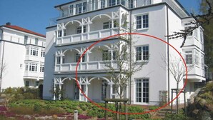 A multi-story building with a symmetrical facade, large windows, and a balcony on the upper floor.