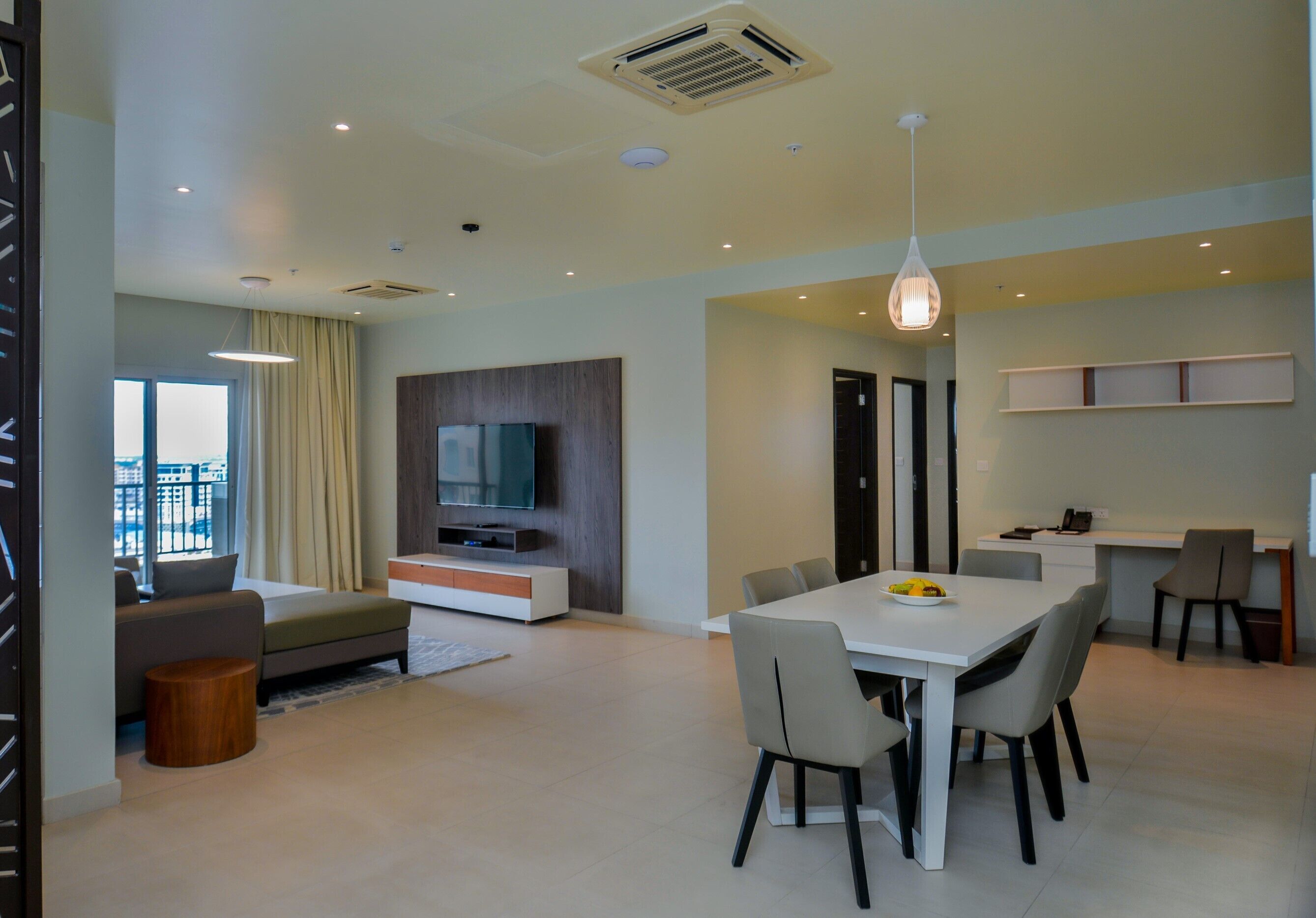 A modern living room with a sofa, TV, dining table, and chairs.