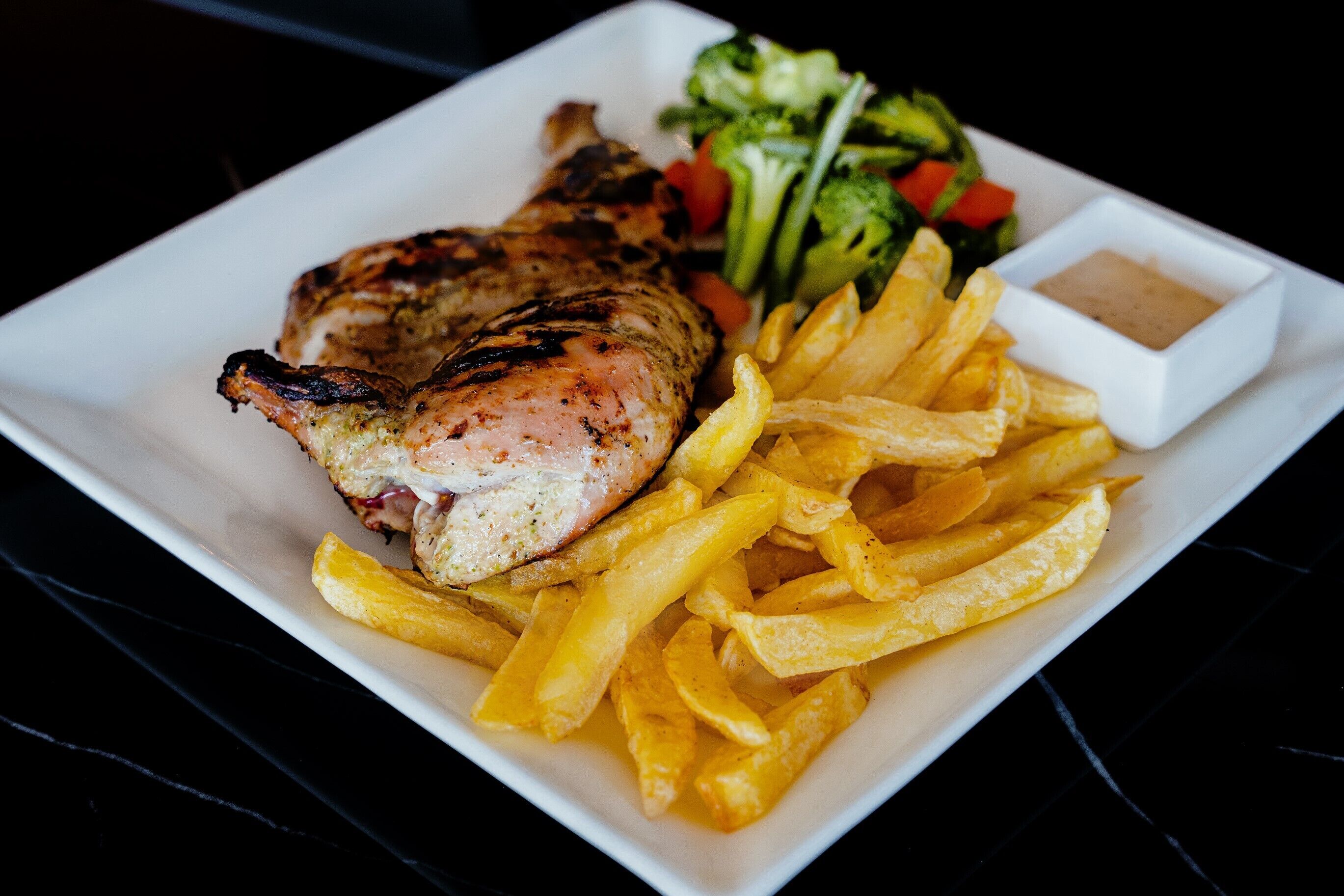 Um prato com carne grelhada, batatas fritas e uma salada.
