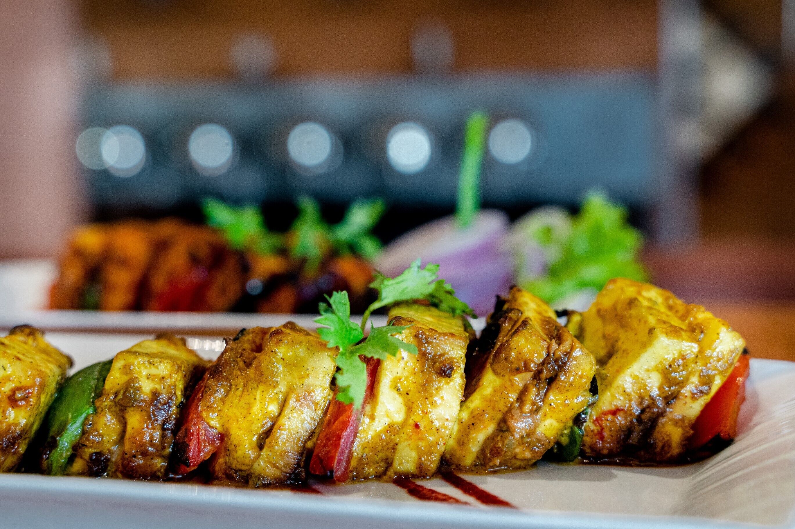Un plato de brochetas de pollo marinadas, adornadas con hierbas.