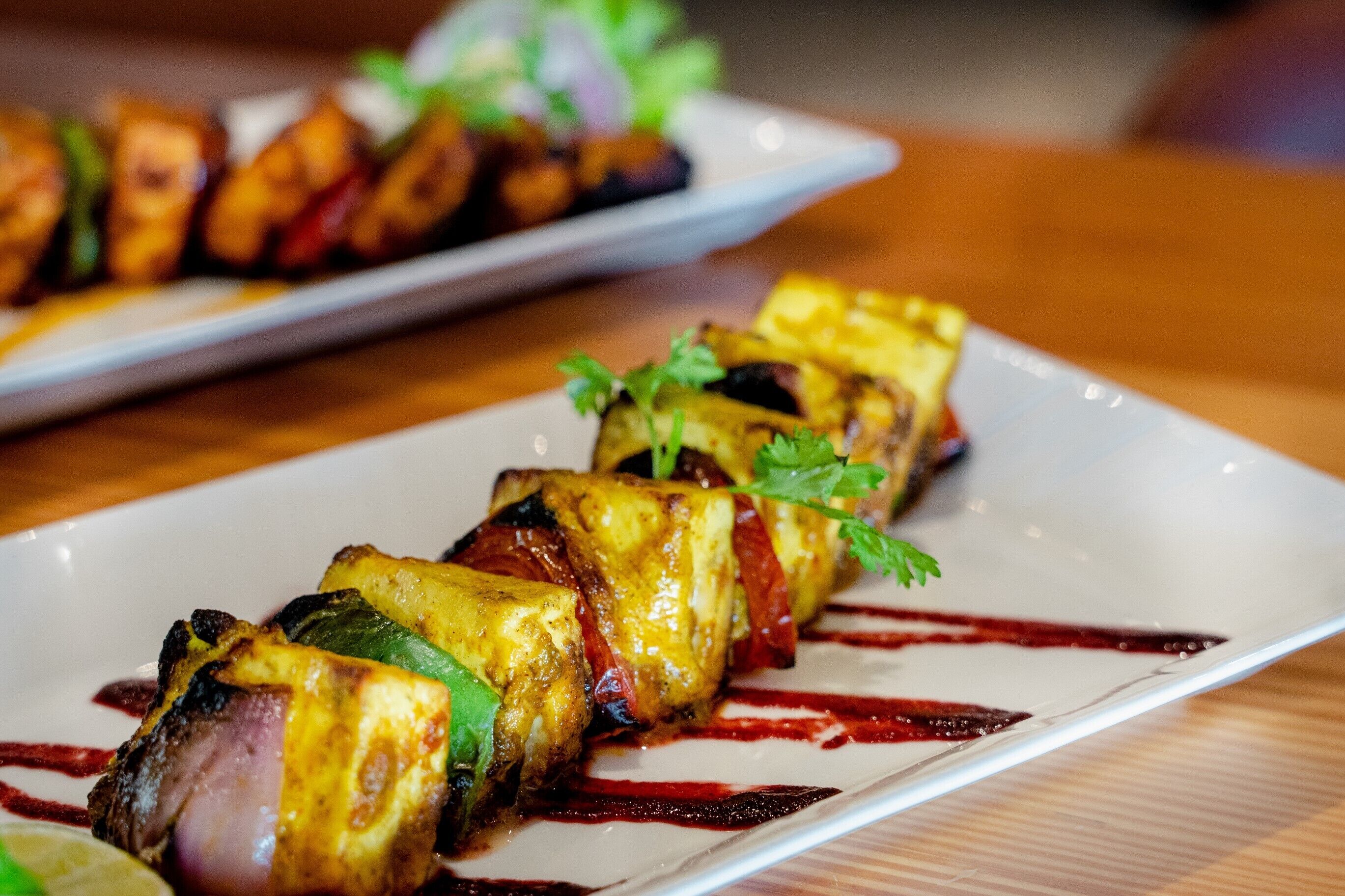 Un plato de brochetas a la parrilla con verduras y carne, adornado con perejil.