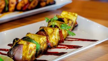 Un plato de brochetas a la parrilla con verduras y carne, adornado con perejil.