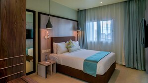 Une chambre d’hôtel avec un grand lit, des tables de chevet, un miroir et une fenêtre avec des rideaux.