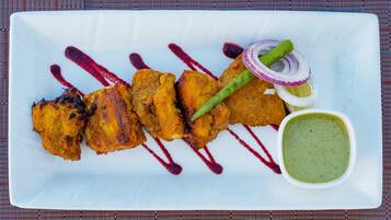 A plate of food with a green sauce and red sauce drizzles.