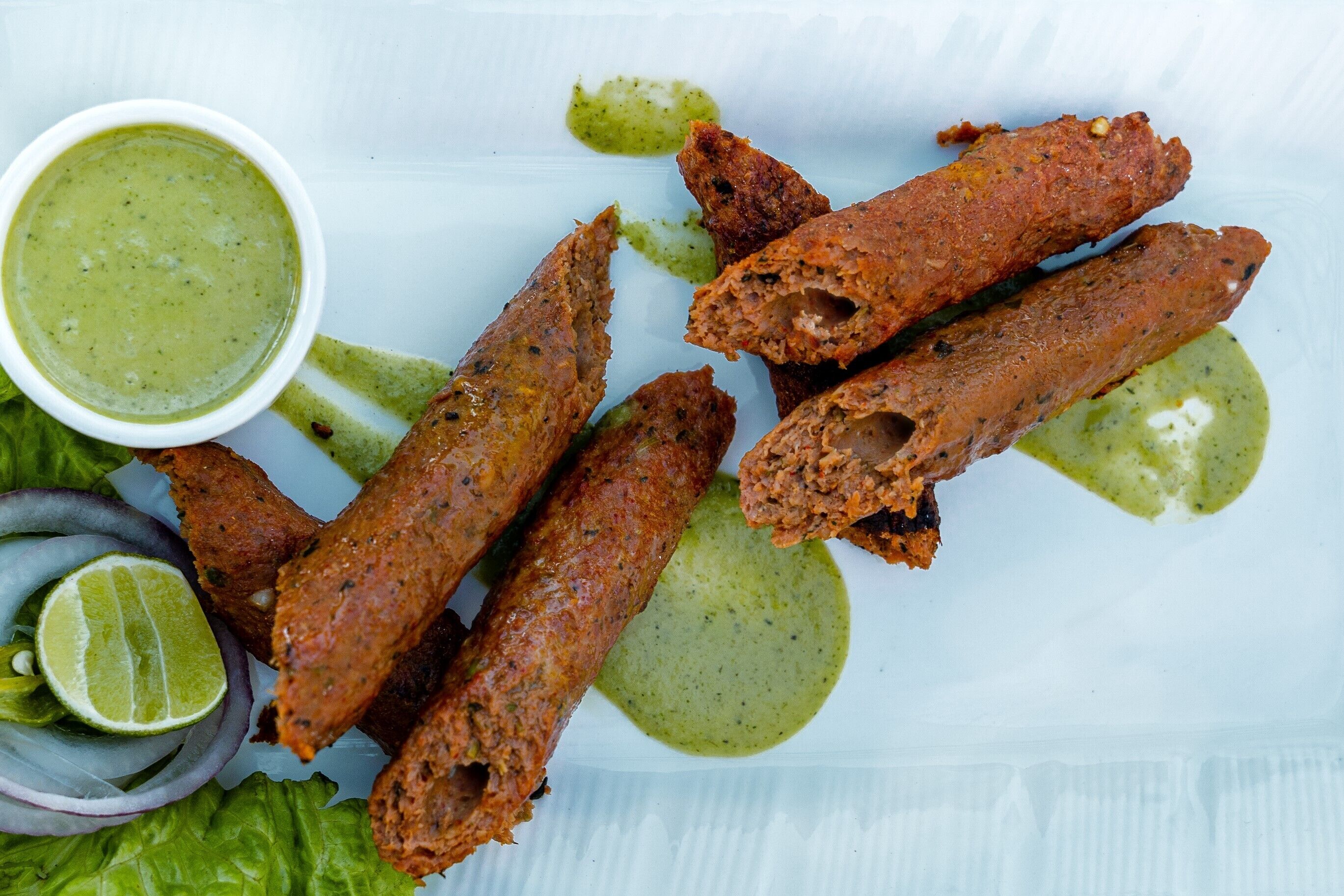 Un plato de carne frita con salsa verde y gajos de lima.