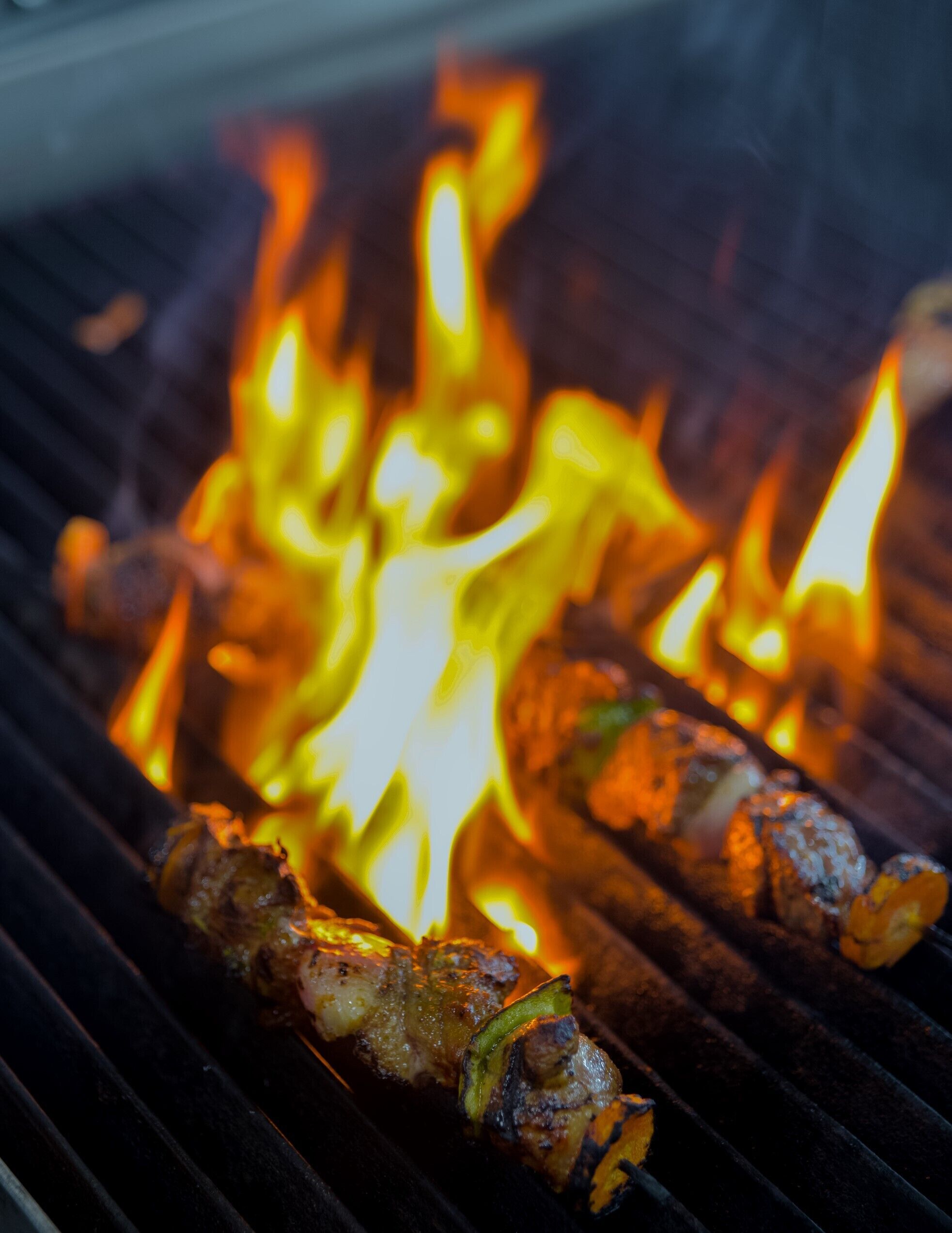 A grill with skewers of meat and vegetables over an open flame.