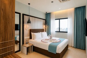 A hotel room with a bed, bedside table, and a view of the city.