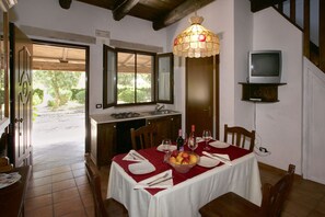 A dining area with a table set for two, a bowl of fruit, and a television mounted on the wall. - Holiday Home in Trinitapoli near Adriatic Sea (Trinitapoli, BARLETTA)