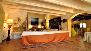 A dining area with a table set for a meal, a lamp, and a bookshelf in the background.