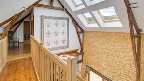 A high-ceilinged room with skylights, wooden beams, and a stone wall.